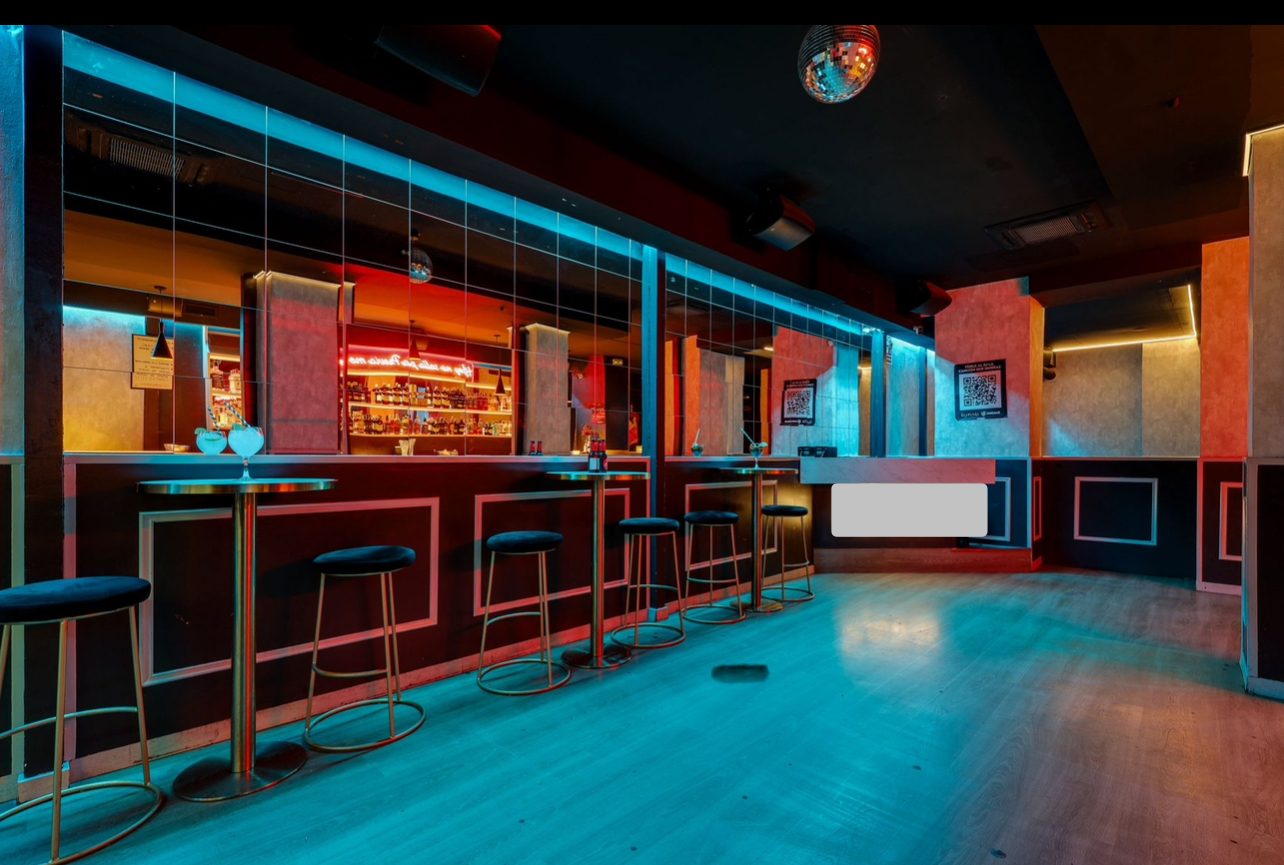 Sala Lila en Barcelona con barra, taburetes altos y pista de baile con iluminación turquesa