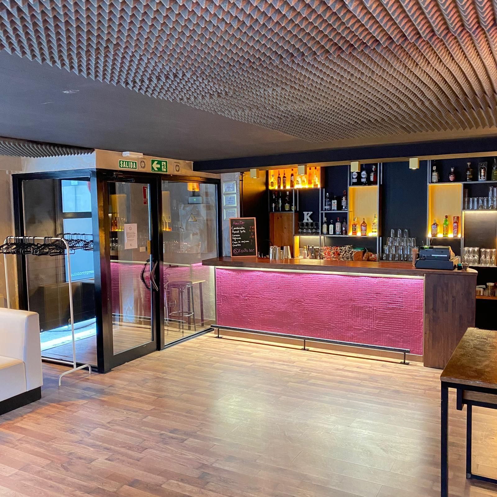 Sala Yellow en Barcelona, local a pie de calle con barra rosa retroiluminada, suelo de madera y acceso acristalado a la calle